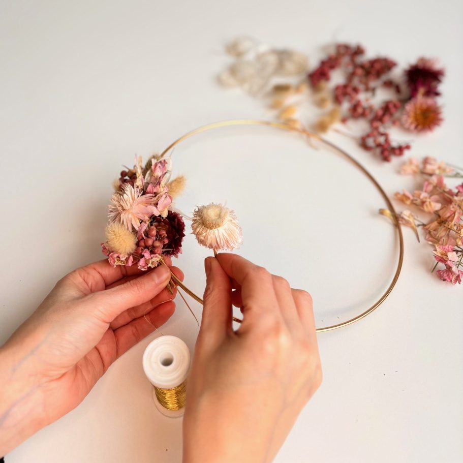 Kreativ Workshop, Kranz binden mit ungefärbte Trockenblumen, München, Florales Design Hände gestalten einen Kranz mit getrockneten Blumen in rosa und creme.